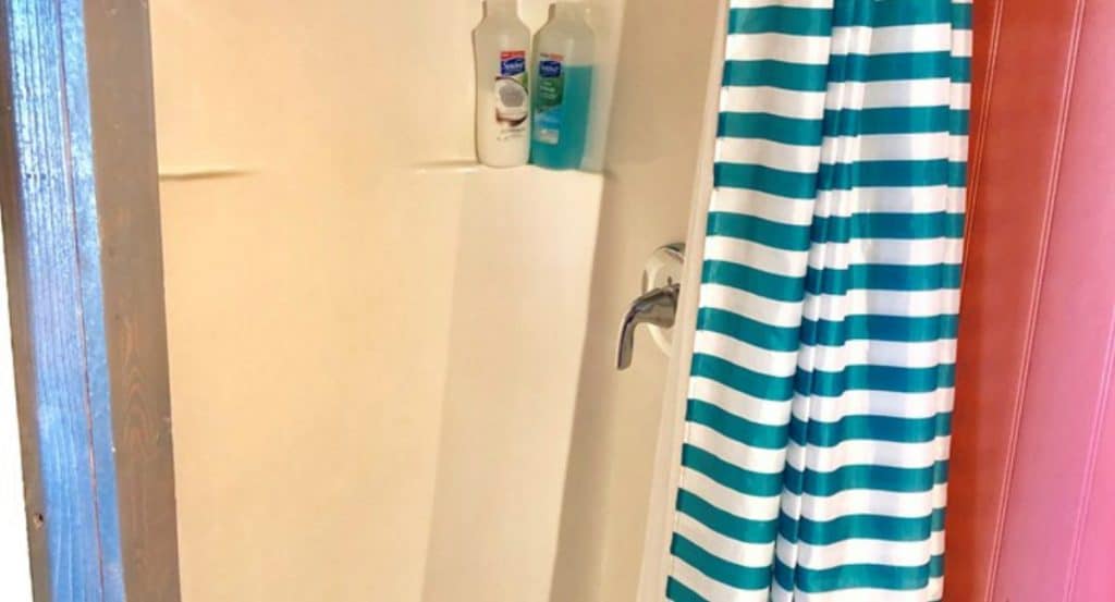 Stand up shower with blue striped curtain