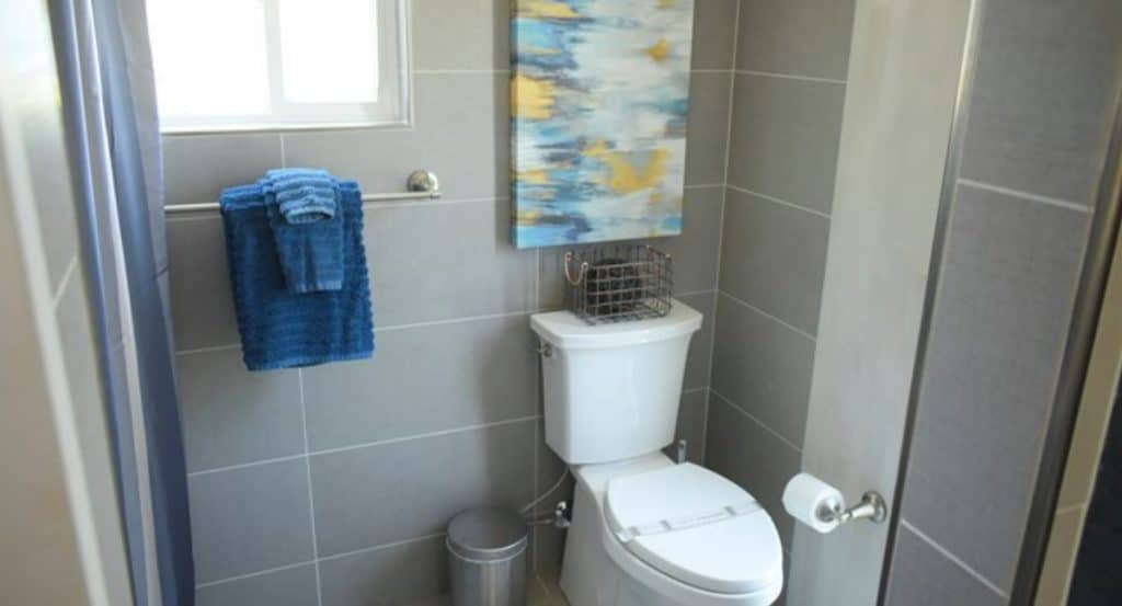 Toilet with gray tile walls in tiny home