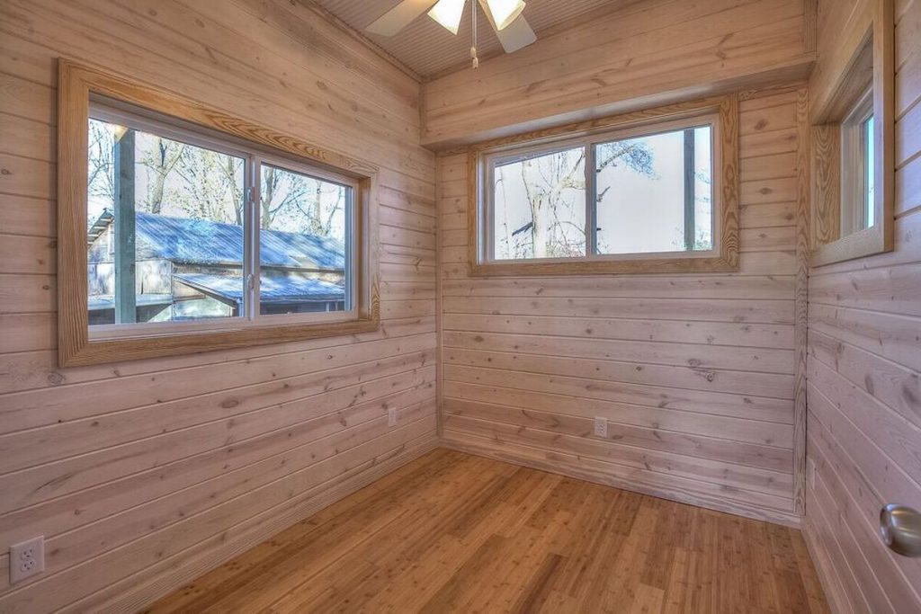 Bedroom with wood paneling and large windows