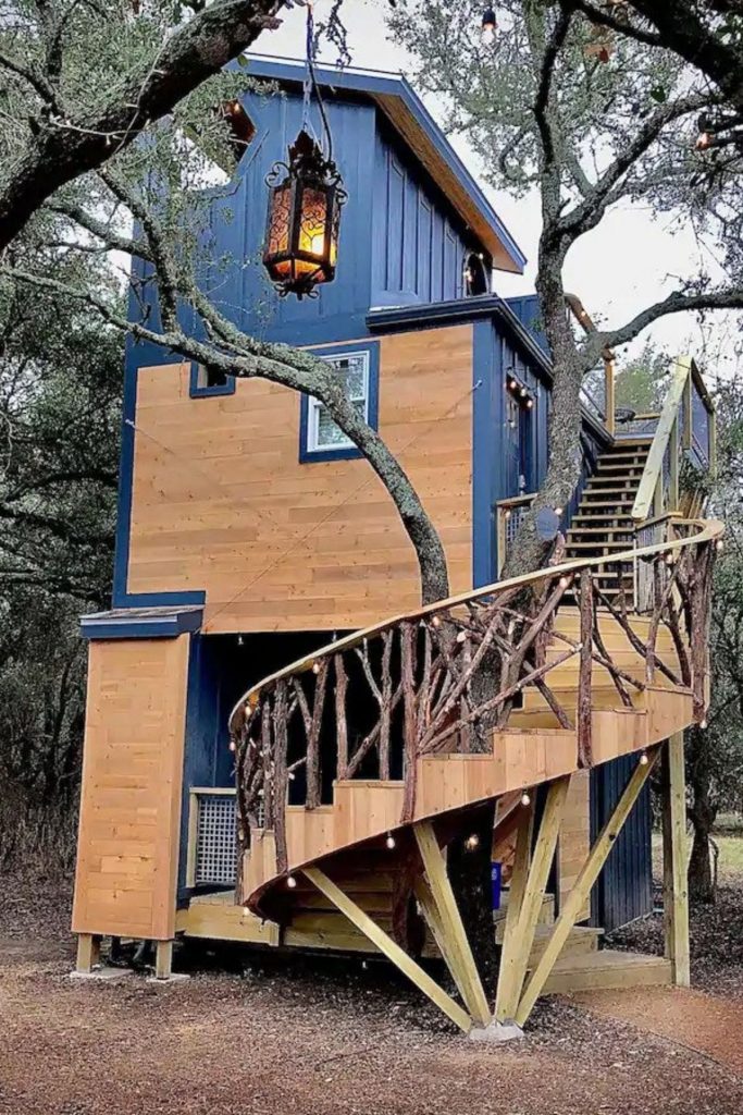 The Acorn tiny home with blue siding and spiral staircase