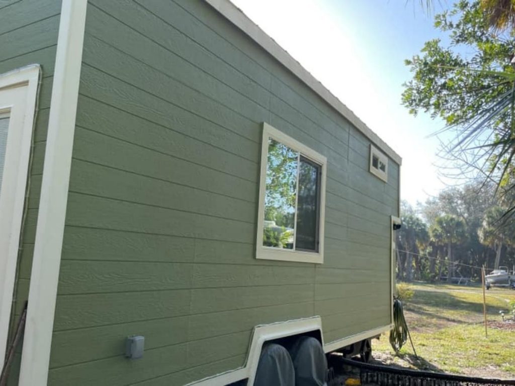 Green tiny house with white trim