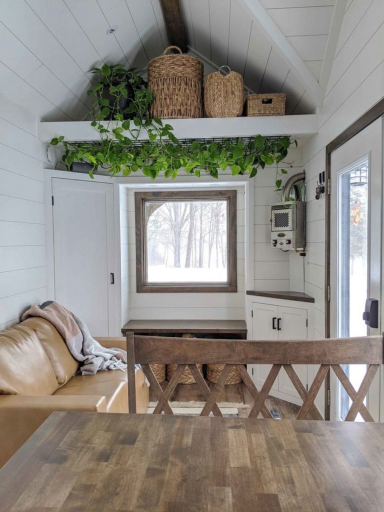 Front window of tiny house with greenery hanging above