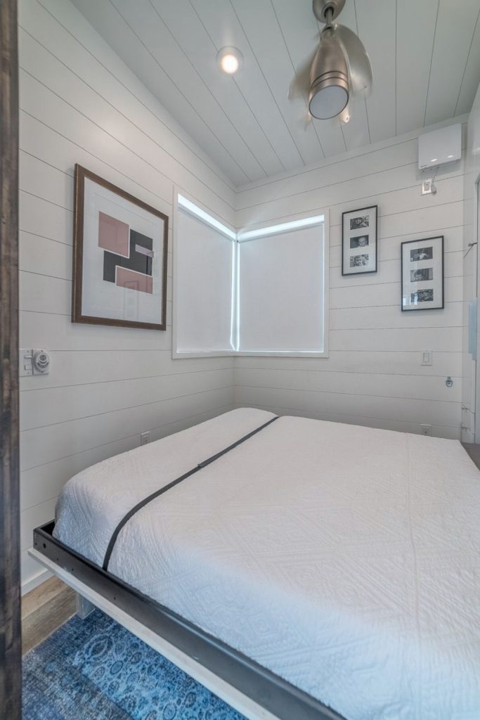Tiny house bedroom with white bed on small stilts