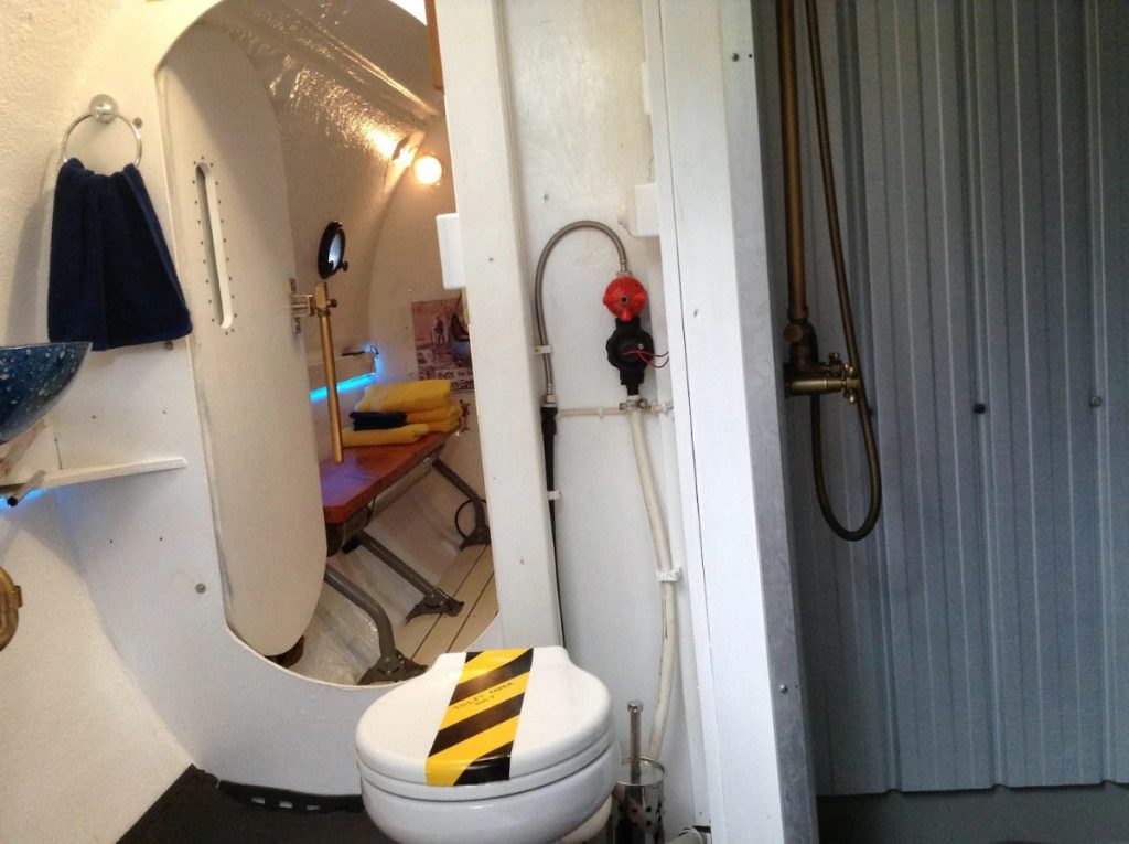 Submarine bathroom with white walls and caution tape on toilet
