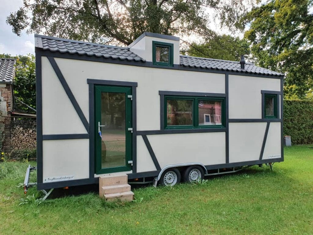 Black and white Bavarian look tiny house on wheels in yard