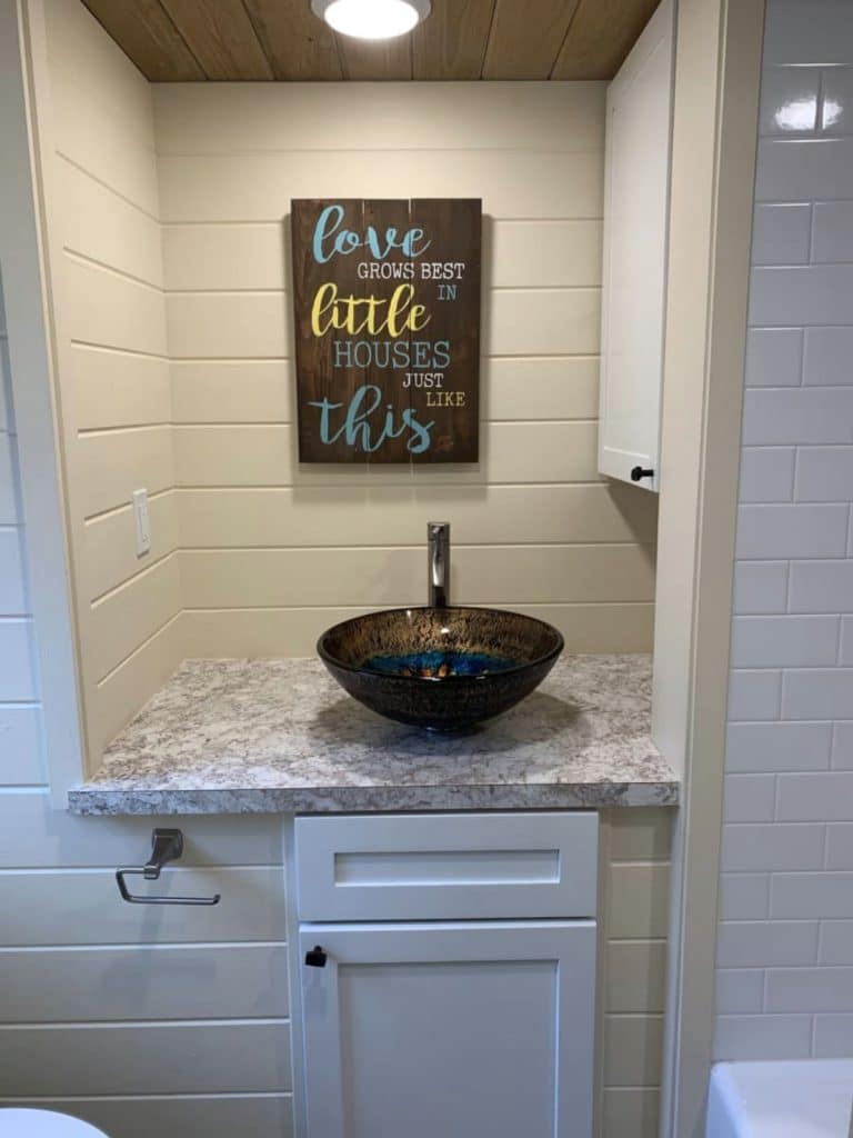 Bowl sink on counter between shiplap walls with sign above