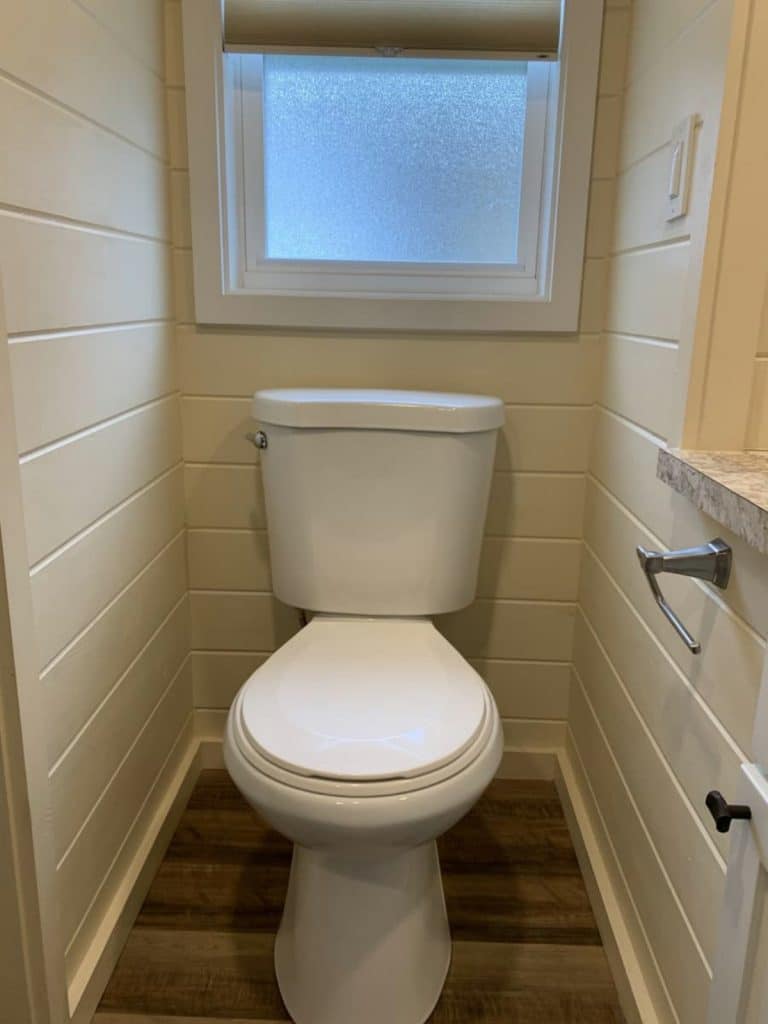 White toilet in corner with shiplap walls