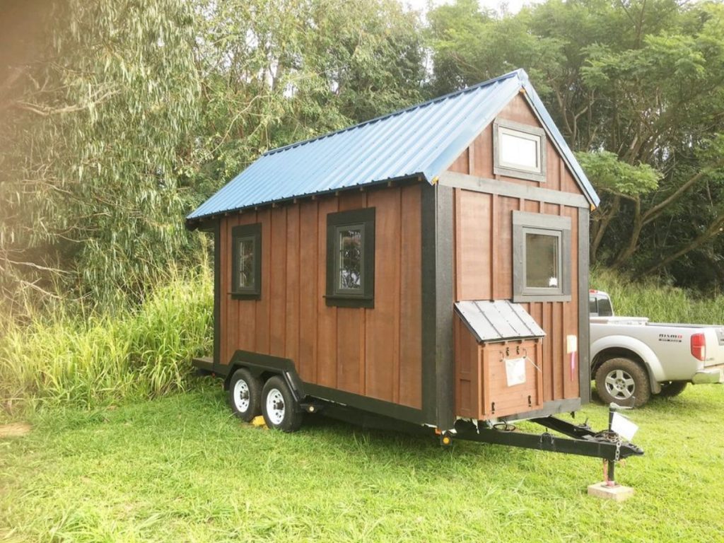 Cedar tiny house with dark corrugated roof on grass