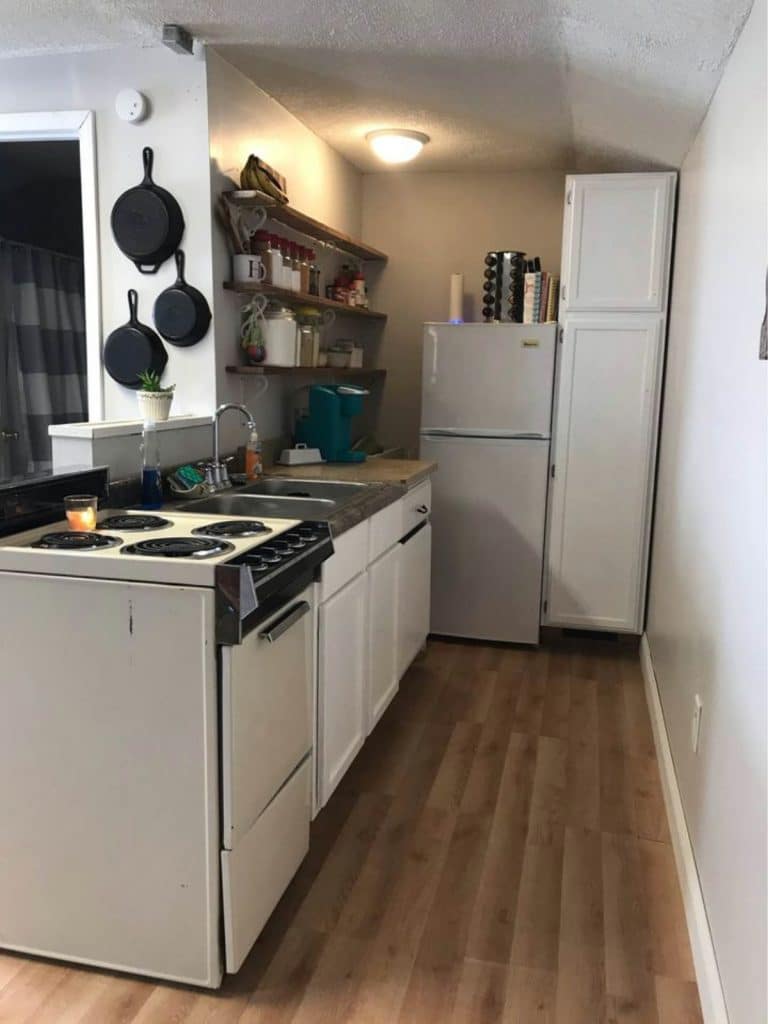 Kitchenette with stove on end and white refrigerator on back wall