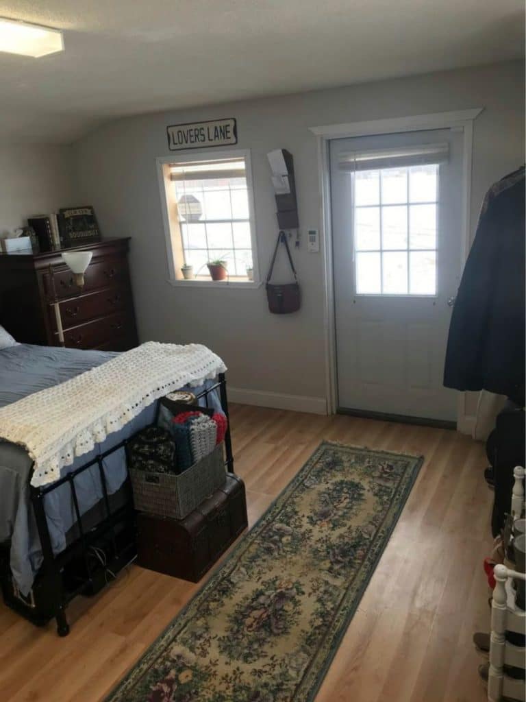 View of end of bed with blue blanket and white door
