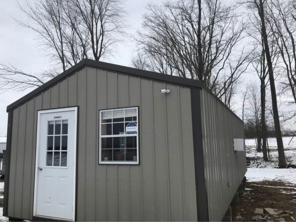 Front of shed with grey siding and white door