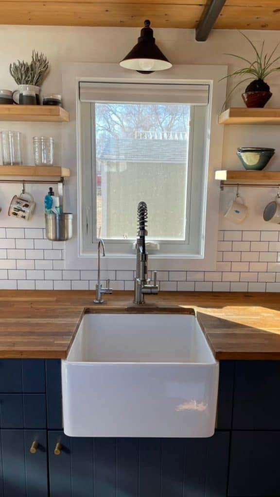White farmhouse sink in butcher block counter by window