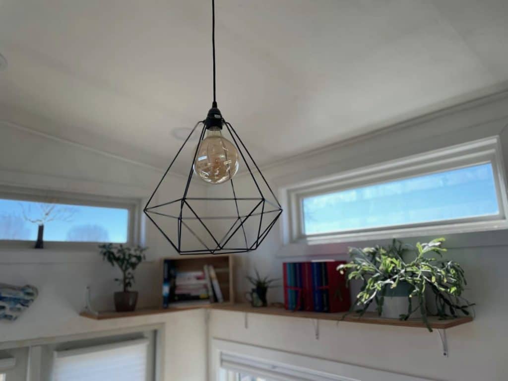 Industrial wire light fixture hanging from white ceiling