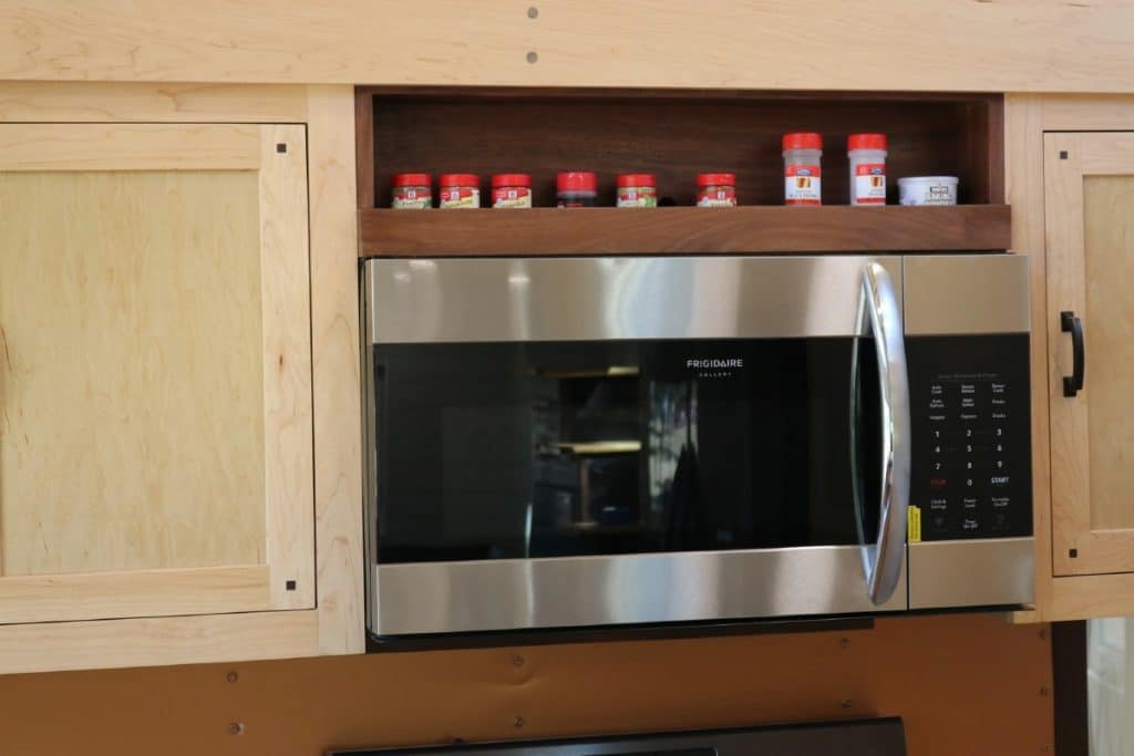 Stainless steel and black microwave in cabinets