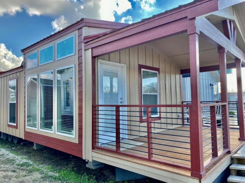 Tan and maroon tiny house with covered porch on lot