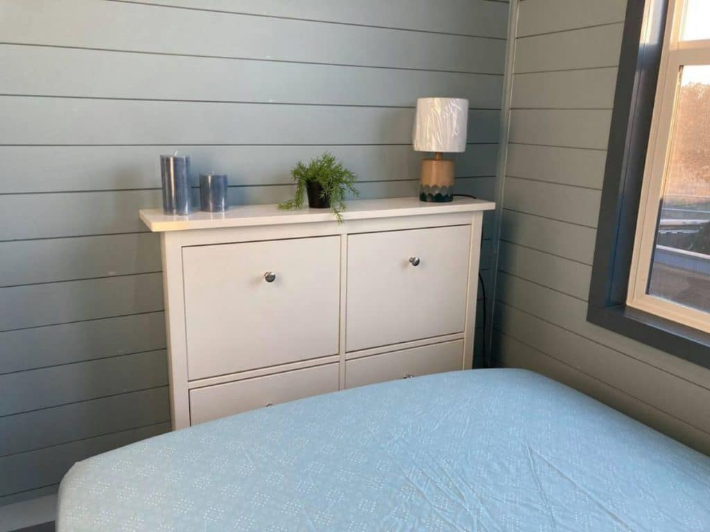 Blue bed with white dresser aginst blue shiplap