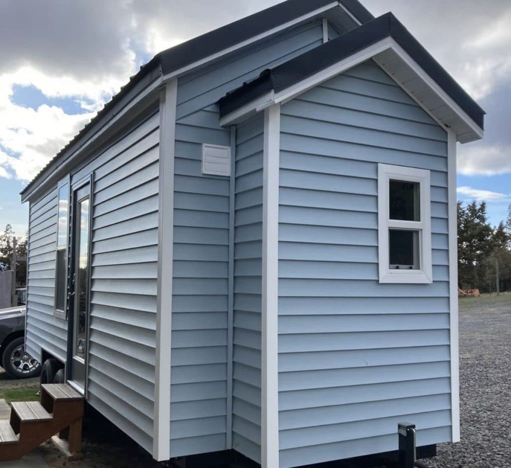 Back of blue tiny home with white trim