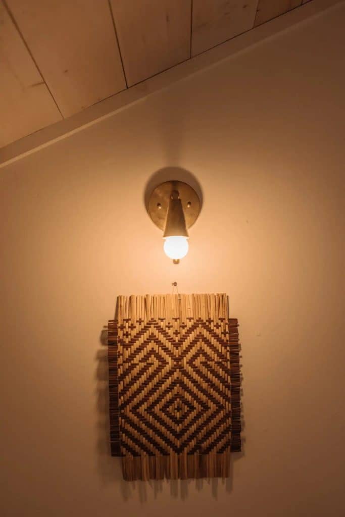 Woven wall hanging under wall sconce