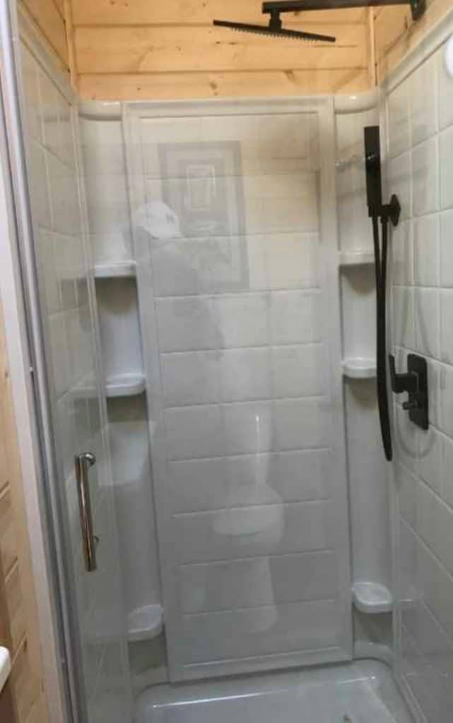 White shower stall with glass door and built-in shelves