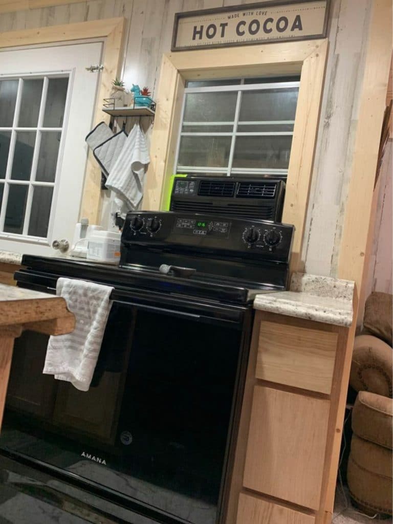 Black electric stove between blonde wood cabinets