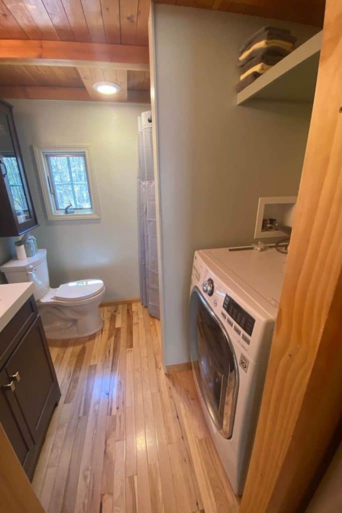 View into bathroom with hardwood stove and washing machine in foreground