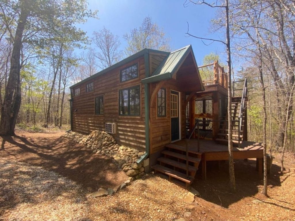 Front of cabin tiny house with green roof and porch with deck roof