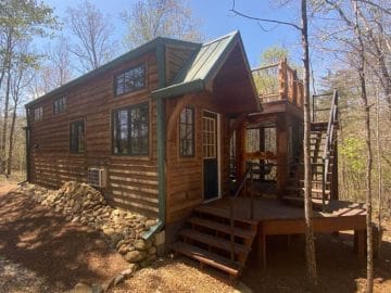 Cabin in woods with porch and deck on roof