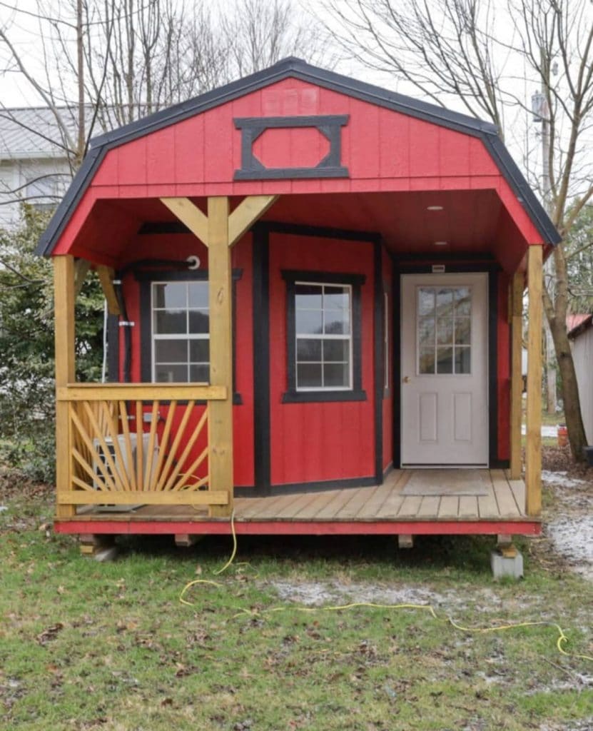 Front of red shed tiny house with wood porch
