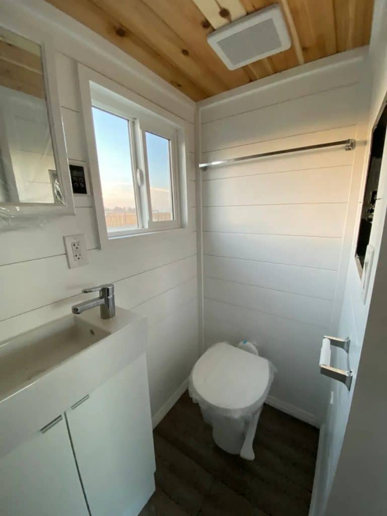 Toilet in white shiplap wall tiny house