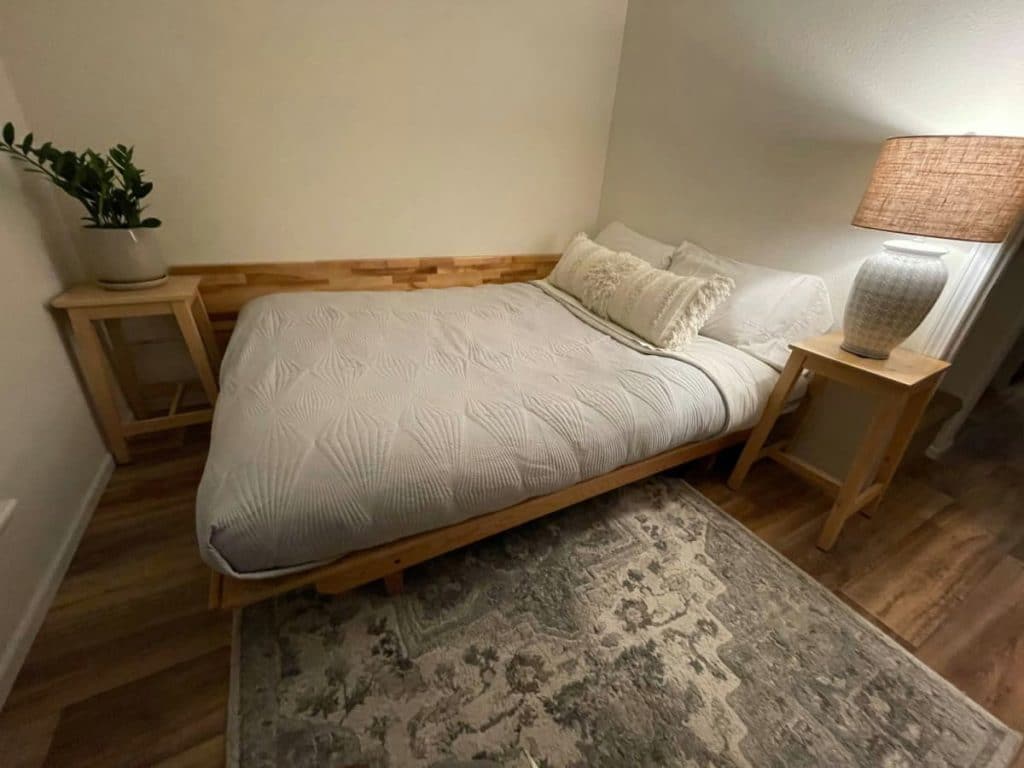 Bed on wooden platform in tiny bedroom