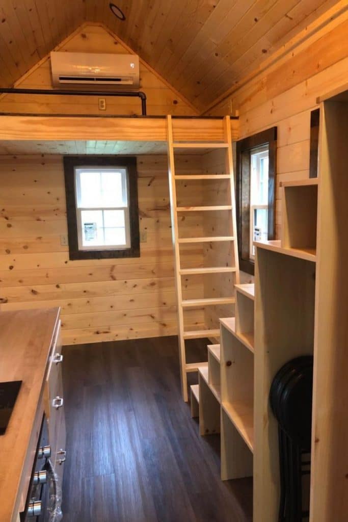 Empty tiny home showing ladder to loft and stairs to loft