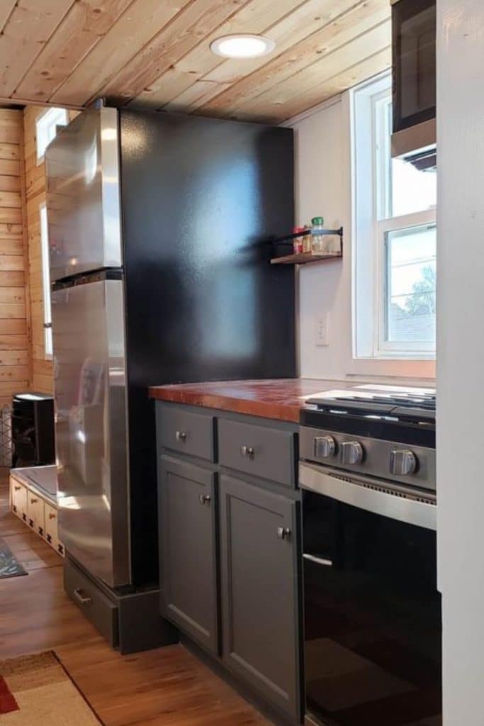 Stainless steel and black refrigerator and stove in tiny kitchen