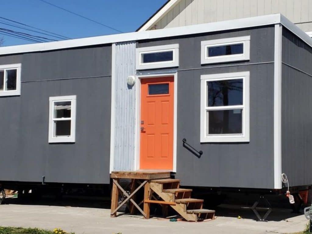 Gray siding and orange door on tiny house on wheels