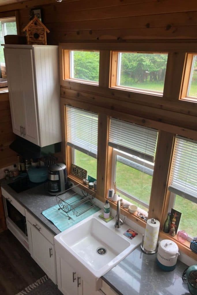 View from loft into kitchen showing large wall of windows and white sink