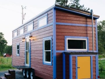 Red and blue tiny house with yellow storage door at end
