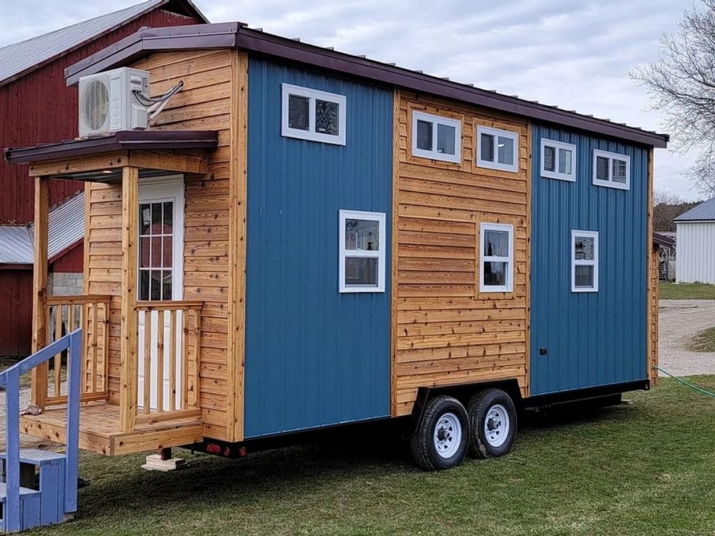 Side of tiny home with small porch and two-toned blue and wood siding