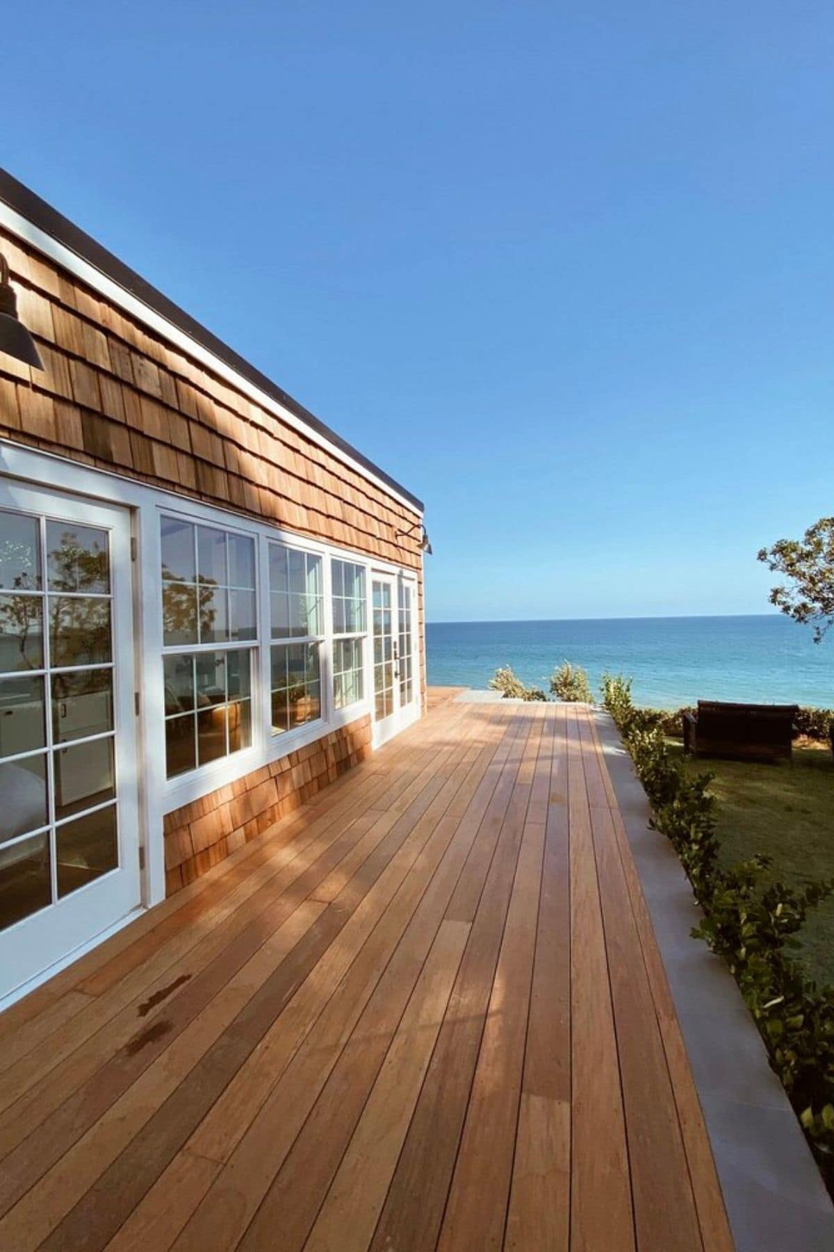 Wood porch length of tiny home with view of ocean in background