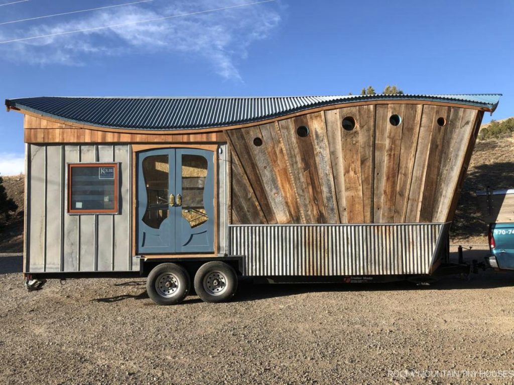 Reclaimed wood and light wood siding on tiny house with sloped roof