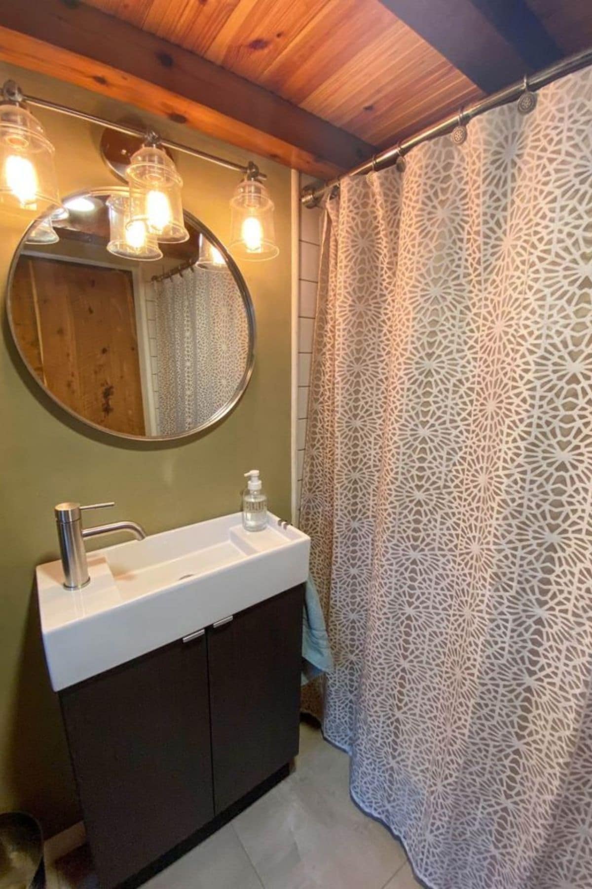 Dark wood vanity with white sink and round mirror