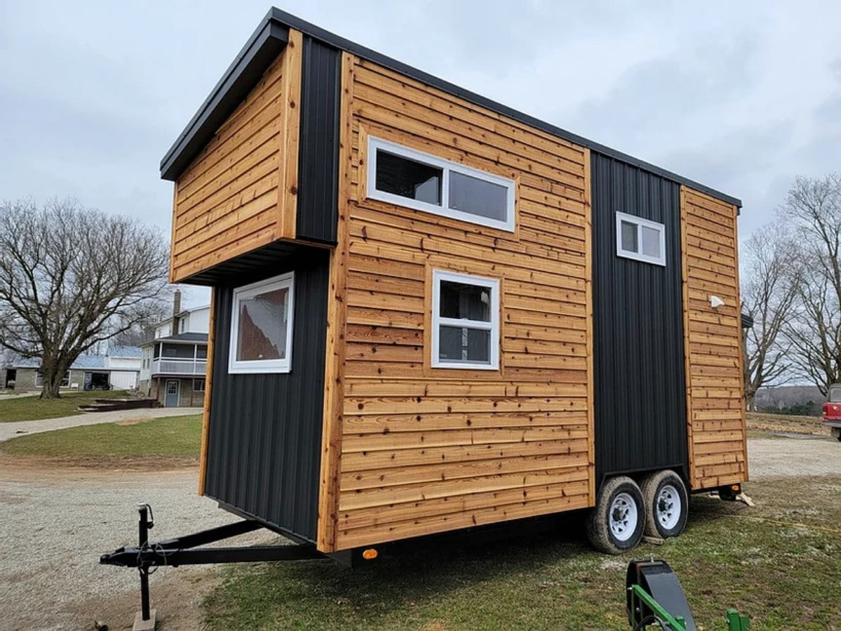 Back side of tiny home on trailer in lot with wood siding