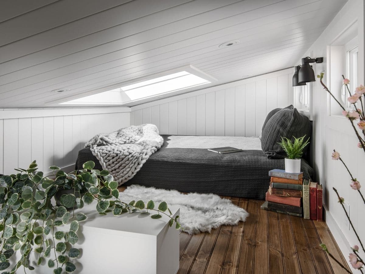 View into loft with white walls skylight and bed against back wall