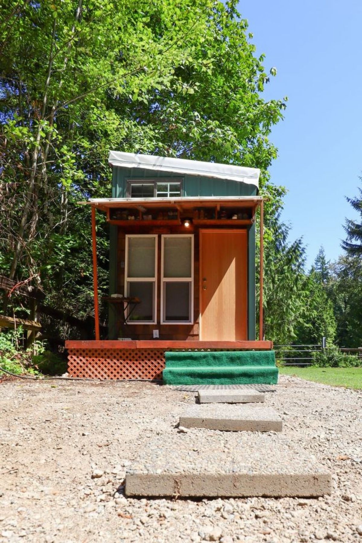 Front porch with small awning on tiny home by trees