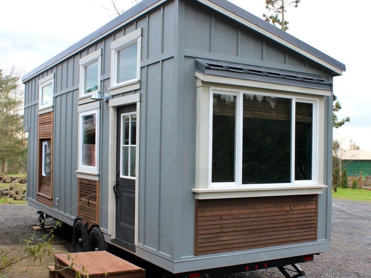 Gray and wood tiny home with white windows and trim