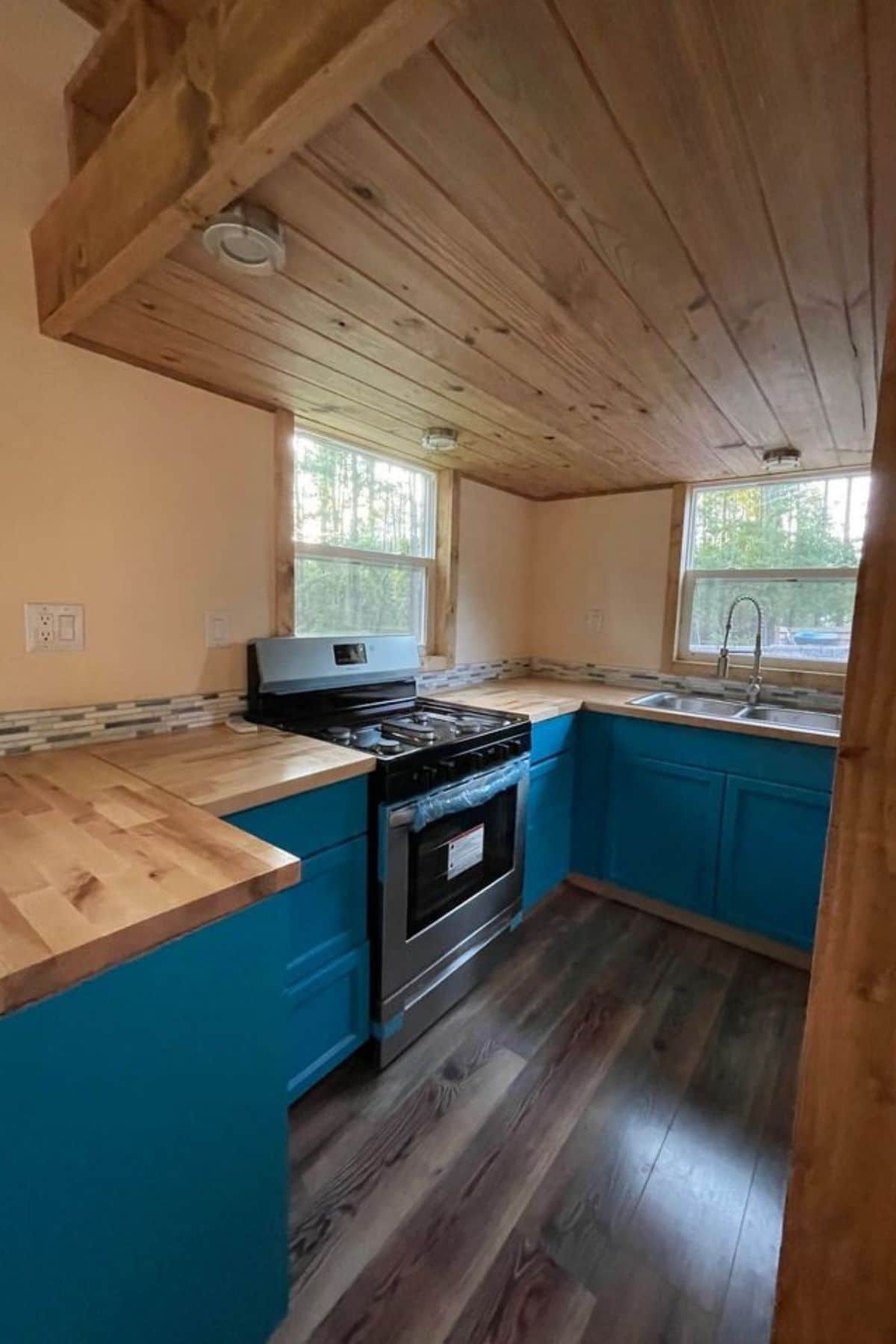 Bright blue cabinets with butcher block counters and stainless steel gas stove