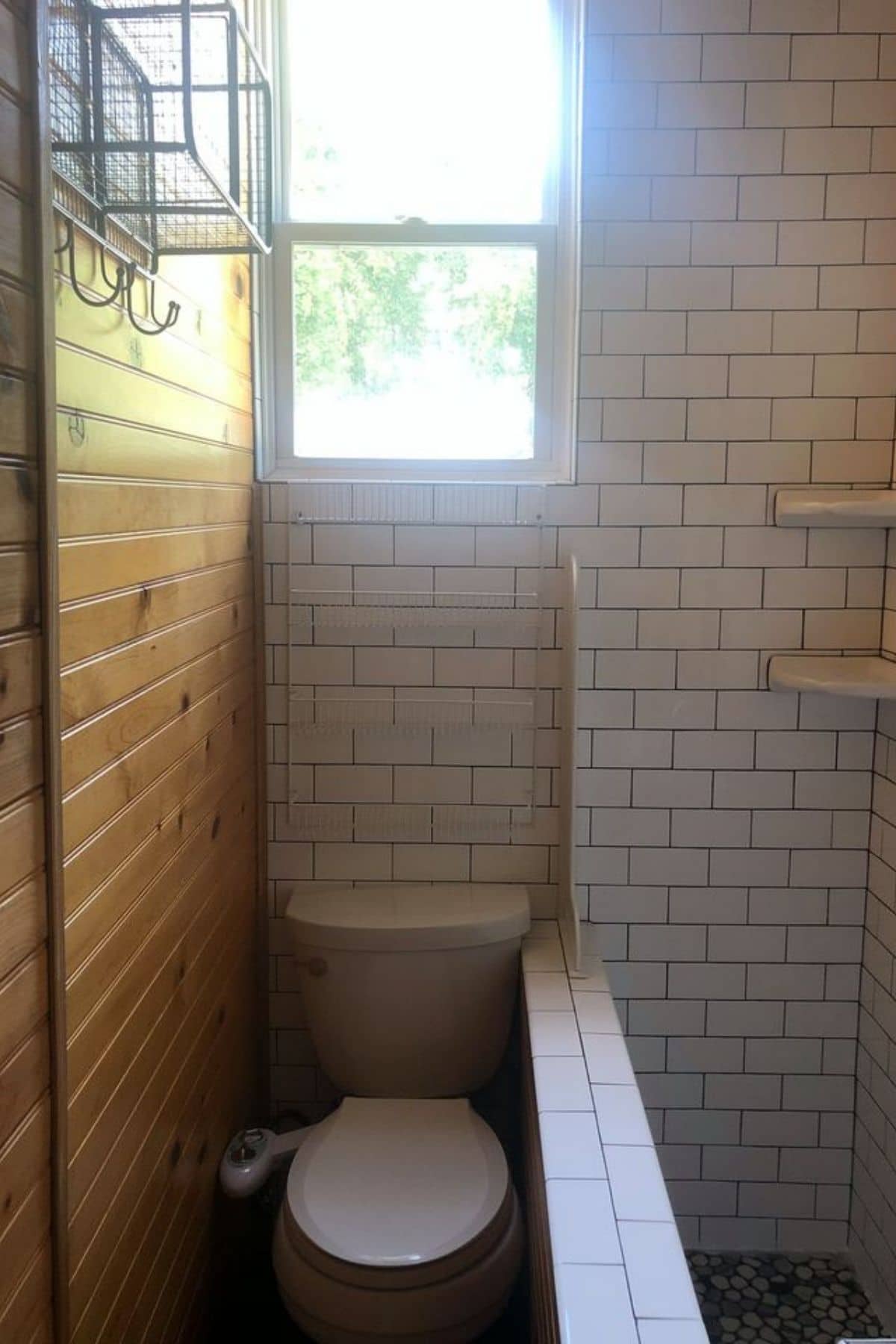 White tiled bathroom wall with flush toilet and wood wall on left