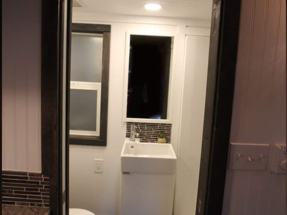 View into bathroom from doorway with mini sink and window to left