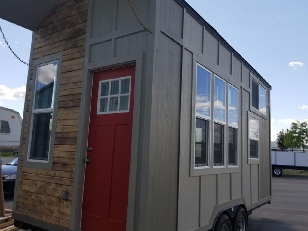 Front and side of gray tiny home with dark red door on end