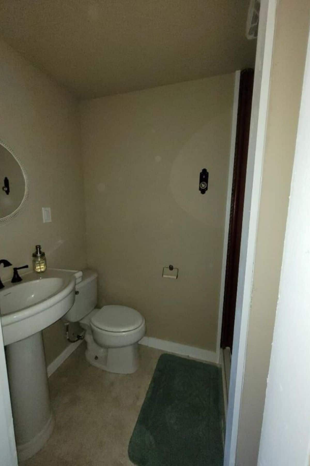 Bathroom with flush toilet and pedestal sink on left walli