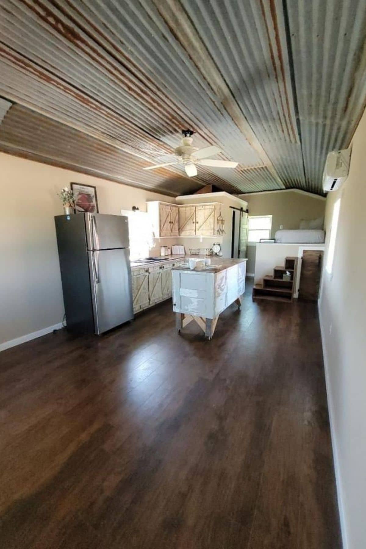 Living room in tiny home with wood floors and island in background