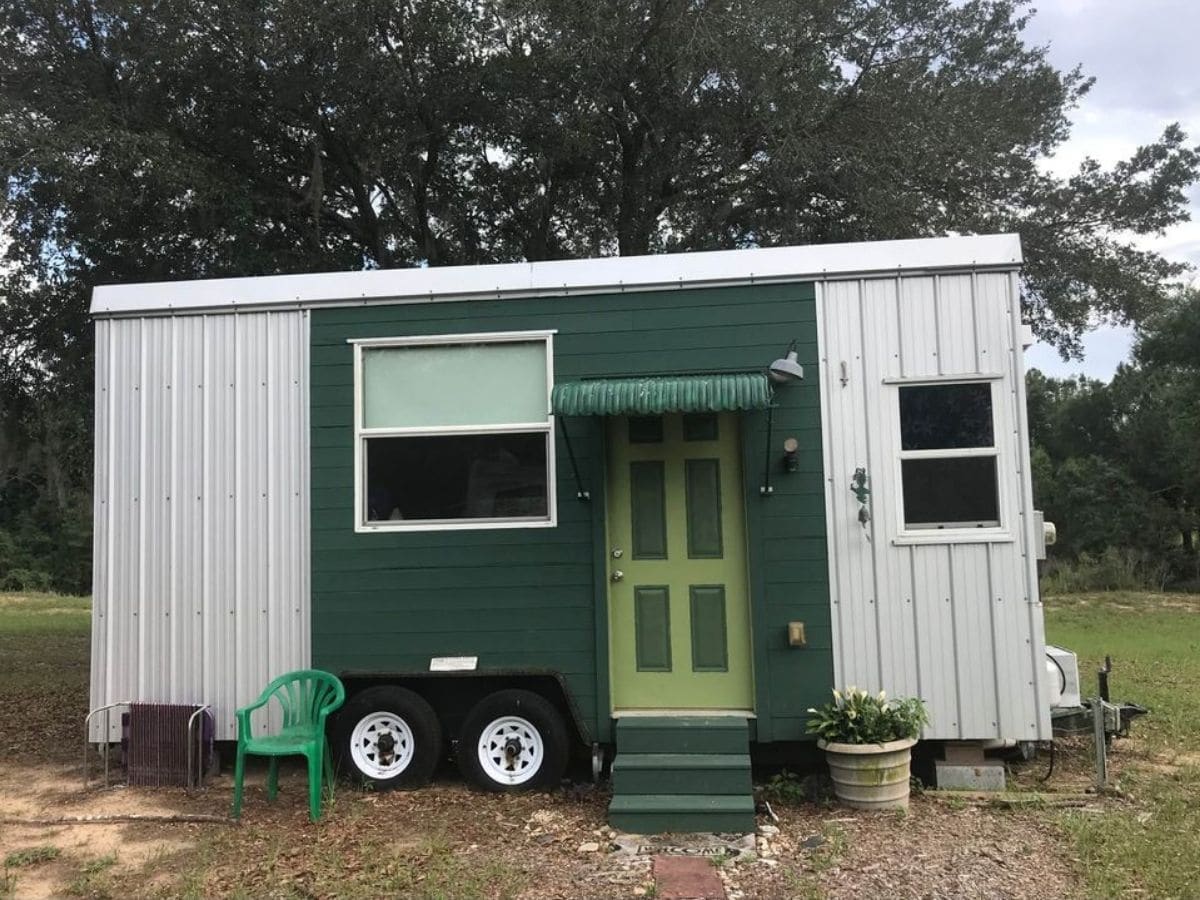 Tiny house on wheels with white and green siding and lime colored door